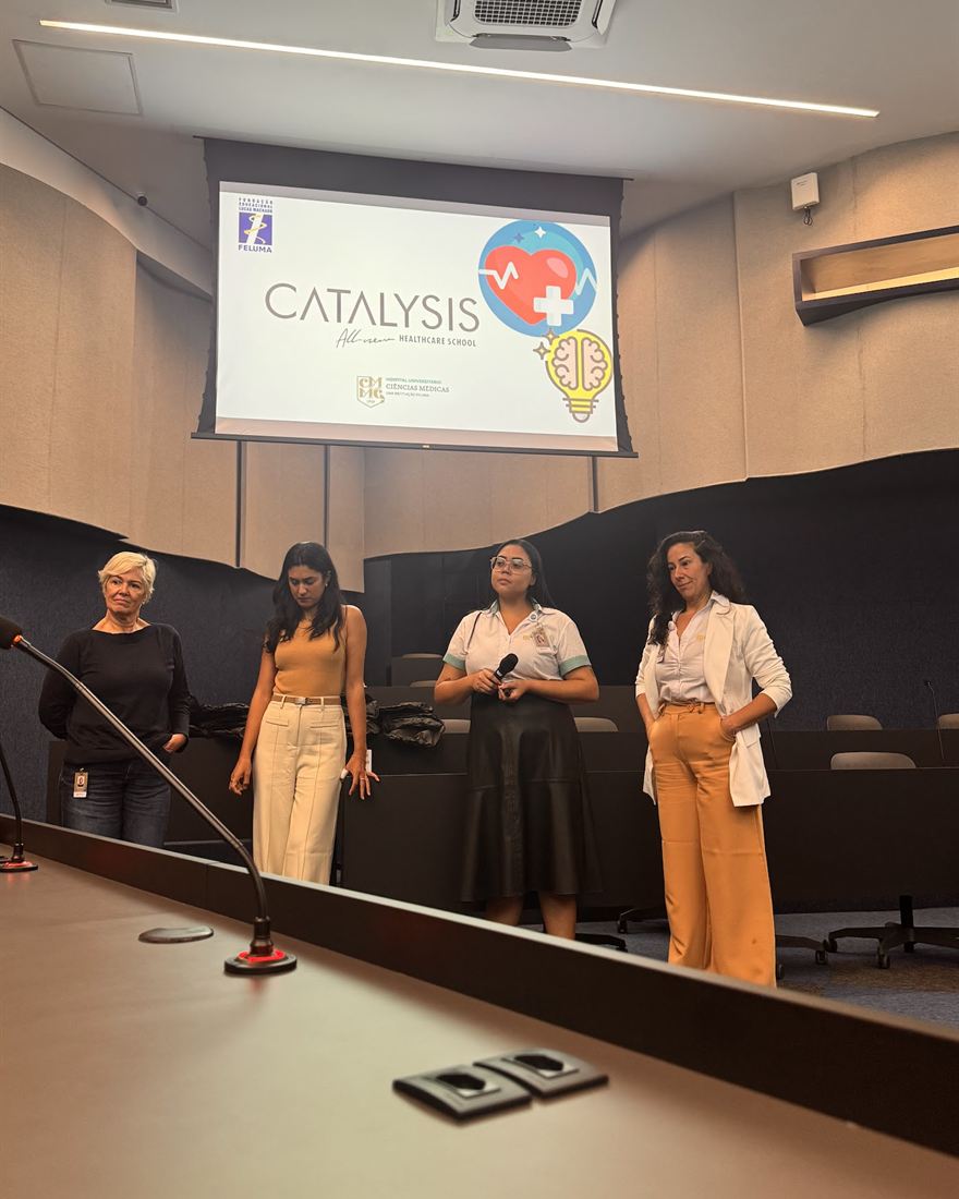 Um time de participantes no palco, diante da tela com a marca Catalysis